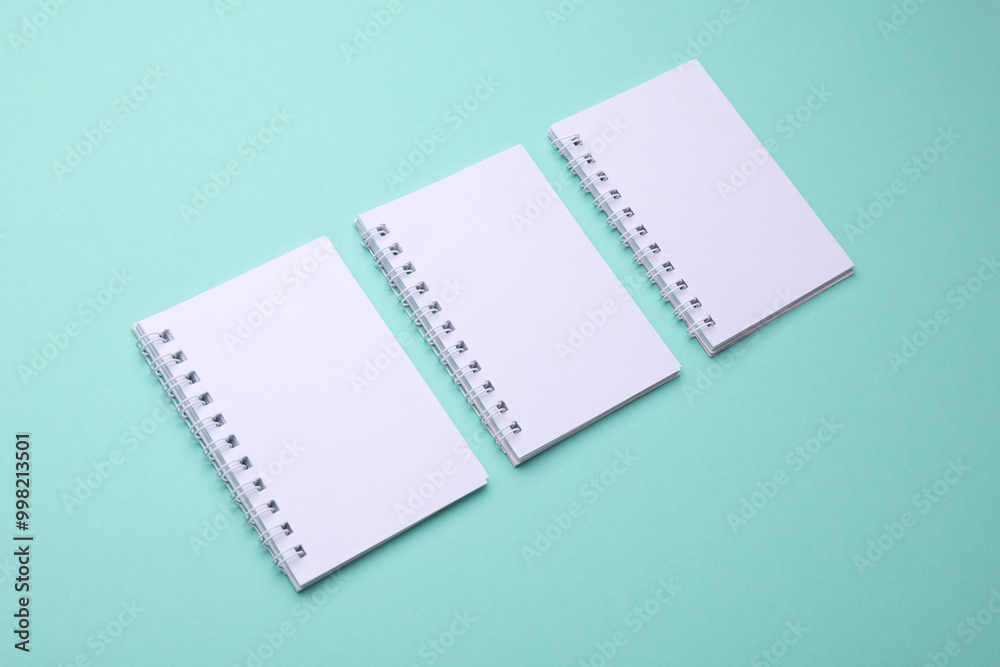 Group of Blank white spiral notebooks on mint green background Group of Blank white spiral notebooks on mint green background
