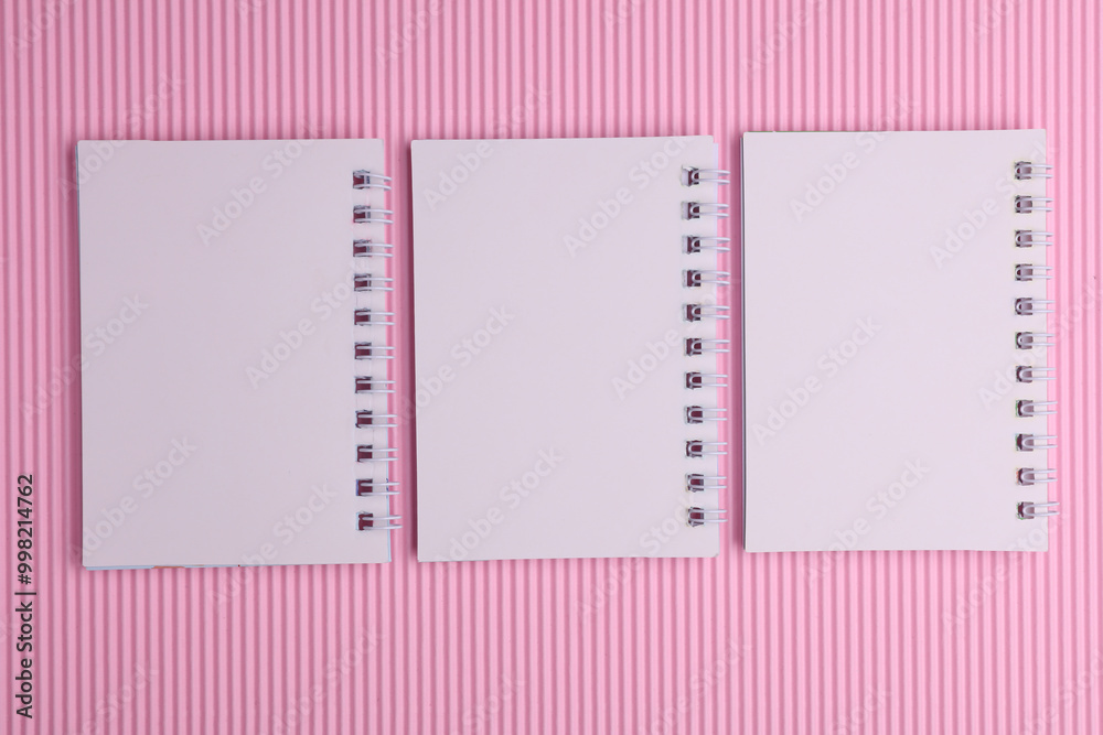 Group of white blank spiral notebooks on pink background Group of white blank spiral notebooks on pink background