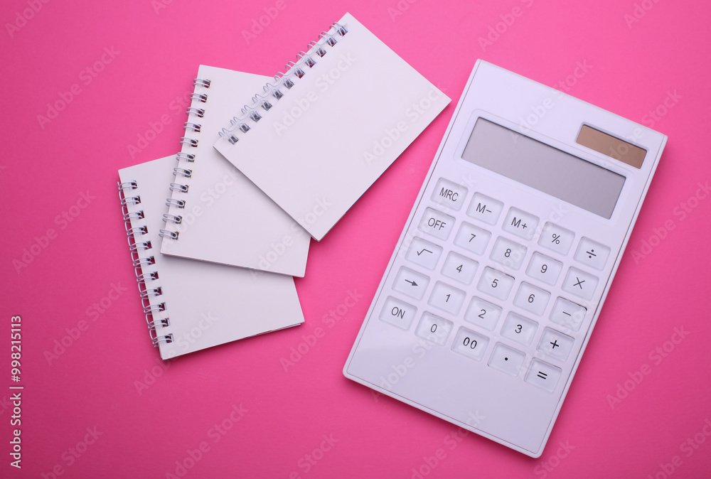 Group of Blank white spiral notebooks with calculator on pink background Group of Blank white spiral notebooks with calculator on pink background