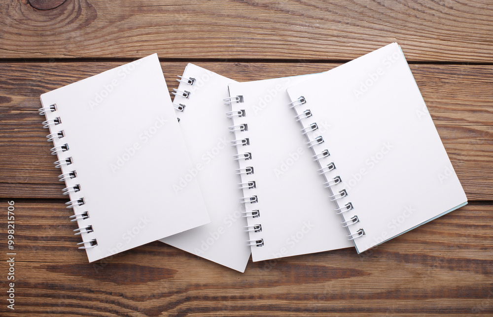 Group of white blank spiral notebooks on wooden background Group of white blank spiral notebooks on wooden background