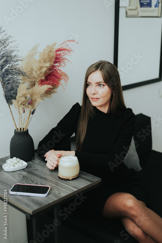 Beautiful girl with a mug of coffee with milk at the table