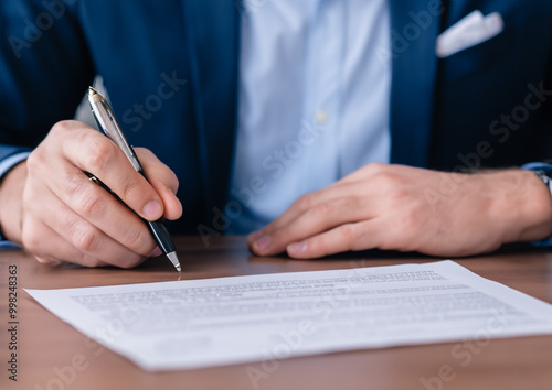 businessman sitting at desk holds pen signing contract paper, lease mortgage, employment hr or affirm partnership 