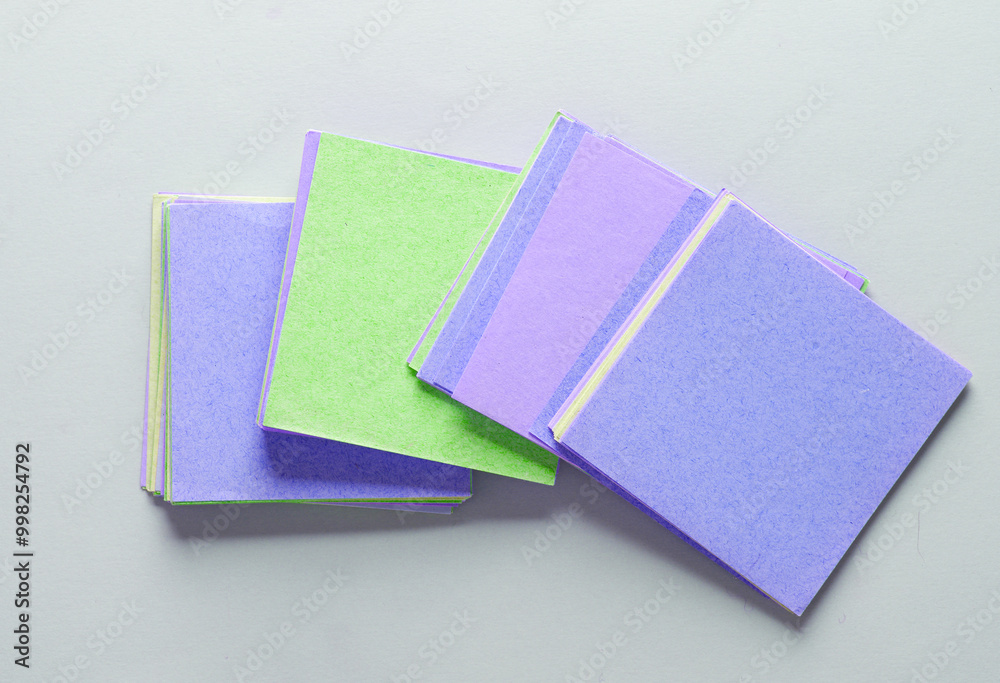 Stack of colored square memo sheets of papers on gray background. Top view