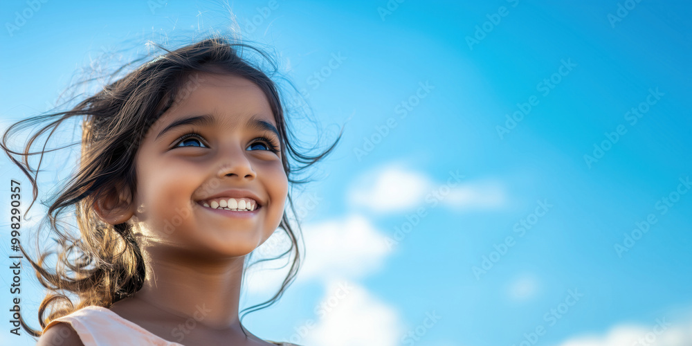 Looking up and smiling indian child, closeup portrait with blue bright sky on the background. Summer vacation concept template. Looking up and smiling indian child, closeup portrait with blue bright sky on the background. Summer vacation concept template.