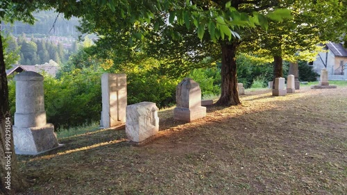 Ancient cemetery under the trees outside the duomo of Tarvisio, Italy