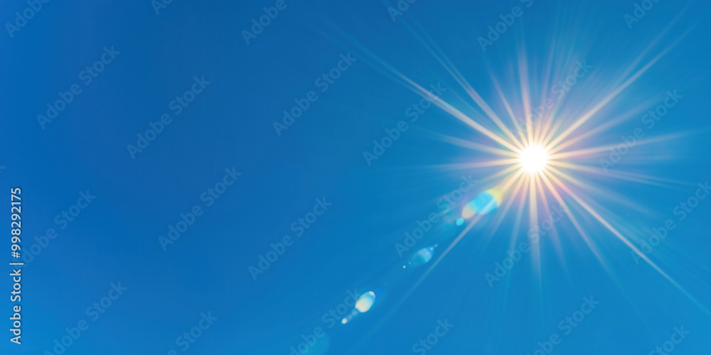 Obraz premium Bright sunburst with lens flares on the clean blue sky, abstract nature photo