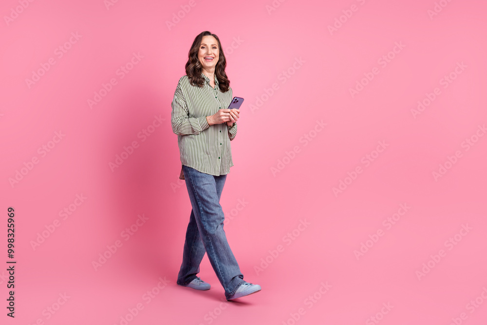 Full body portrait of pretty aged lady walk empty space wear shirt isolated on pink color background Full body portrait of pretty aged lady walk empty space wear shirt isolated on pink color background