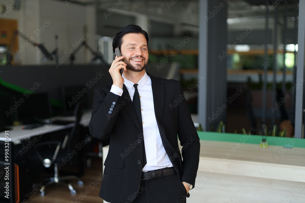 A man in a suit is talking on his cell phone. He is smiling and he is in a good mood A man in a suit is talking on his cell phone. He is smiling and he is in a good mood
