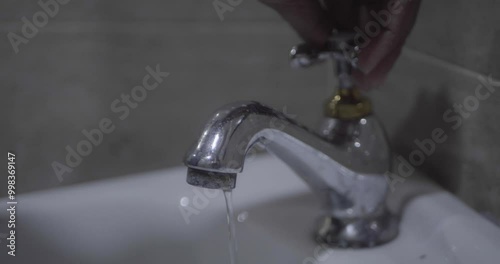 Close up of a man's hand opening the sink faucet.