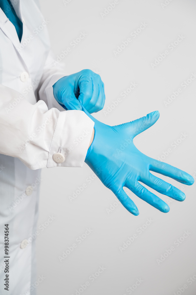 The doctor puts on latex gloves on a white background. 