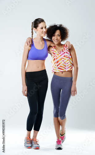 Fitness, women and portrait with hug in studio for training support, teamwork and partner in exercise. Happy, friends and athlete with smile by white background for sports, gym and workout together