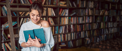 Woman holding open book and looking down shy. Library on the background. Long horizontal banner. lower eyes modestly