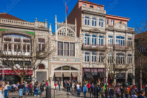 a bustling Portuguese street with ornate historical buildings and a crowd of people enjoying a lively atmosphere, highlighting the architectural beauty and vibrant city life
