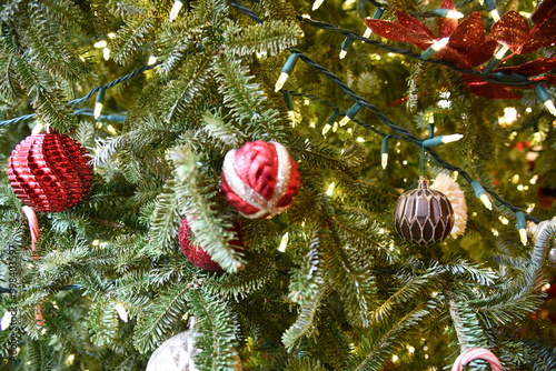 Close view of a Christmas tree adorned with lights and a Christmas ornament