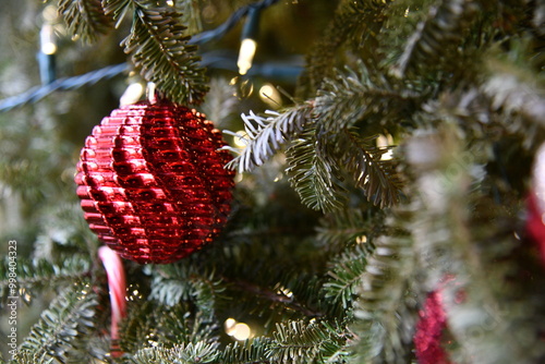 Close view of a Christmas tree adorned with lights and a Christmas ornament