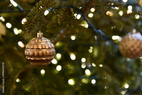 Close view of a Christmas tree adorned with lights and a Christmas ornament