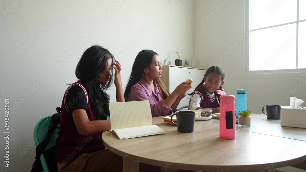 Asian Family Doing Homework Together While Eating Breakfast On The Table Asian Family Doing Homework Together While Eating Breakfast On The Table