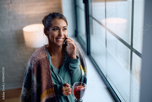 Happy woman making phone call while enjoying in cozy weekend at home.