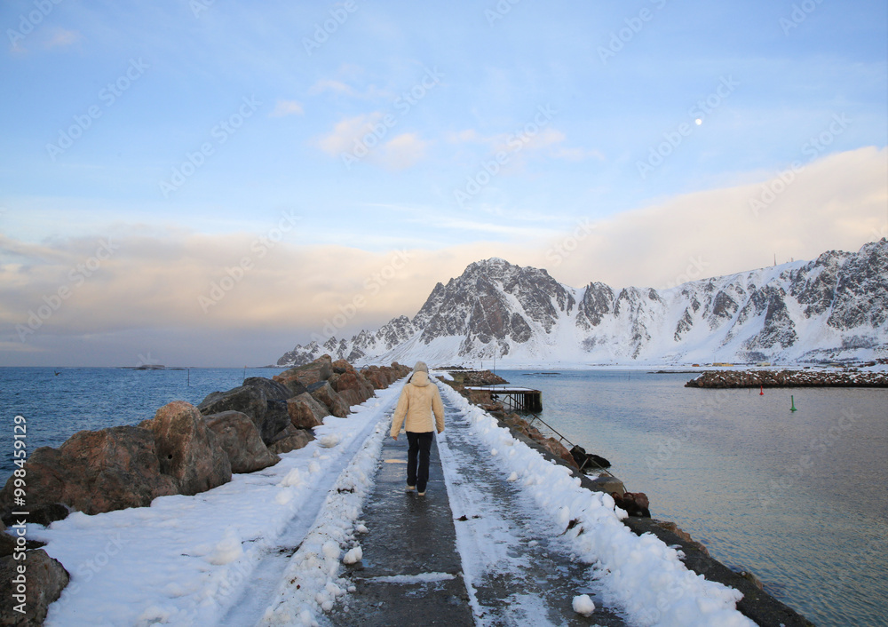 Obraz premium Giovane donna con vestiti invernali cammina sul molo di Bleik, Andoya. Isole Vesteralen, Norvegia