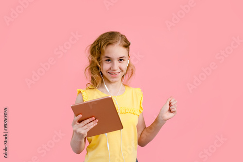 A teenage girl does her homework on a tablet. The student works and communicates with friends photo