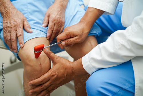 Doctor neurologist testing reflex knee with hammer and show Asian senior scars surgical total knee joint replacement.