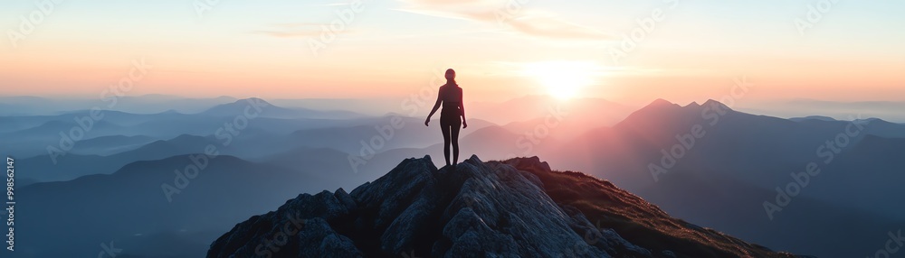 Silhouette of a person standing on a mountain peak at sunrise, overlooking a stunning panoramic view of mountains and valleys in the distance. Silhouette of a person standing on a mountain peak at sunrise, overlooking a stunning panoramic view of mountains and valleys in the distance.