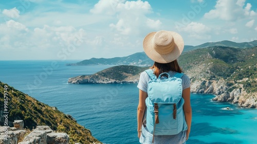 Woman in straw hat overlooking a clear blue sea from ancient ruins, with mountains and a sunny sky in the backdrop.