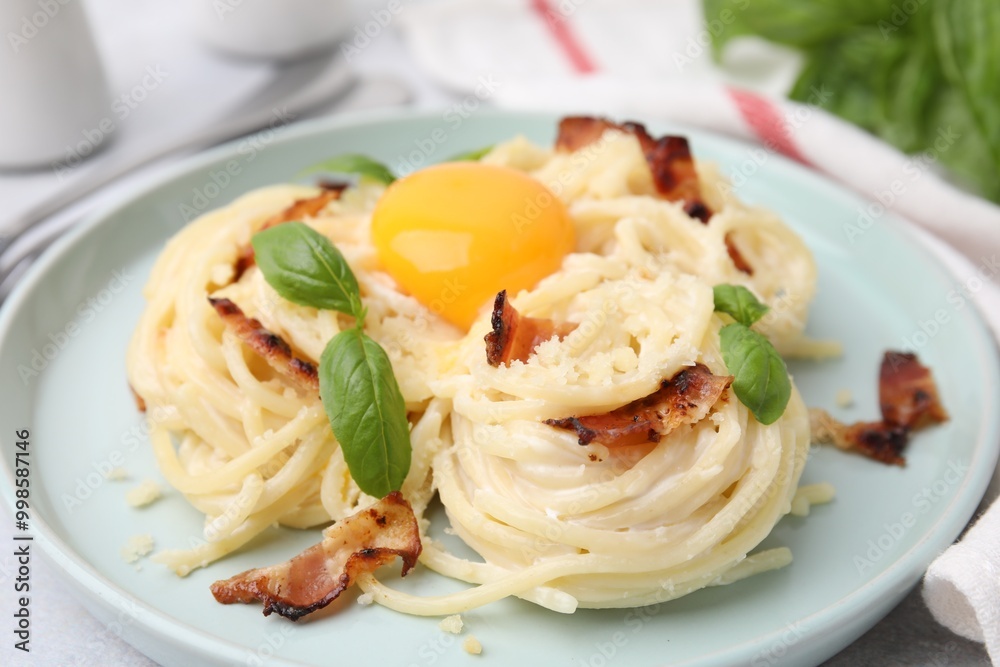 Delicious pasta Carbonara with egg yolk, bacon and basil on table, closeup Delicious pasta Carbonara with egg yolk, bacon and basil on table, closeup