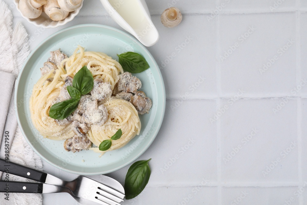 Delicious pasta with mushrooms and basil served on white tiled table, flat lay. Space for text Delicious pasta with mushrooms and basil served on white tiled table, flat lay. Space for text
