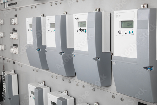 Many smart meters in electrical room of building with defocused ceramic fuses. Digital meter transmits energy consumption. Electric energy use is recorded and transmitted automatic. Selective focus.