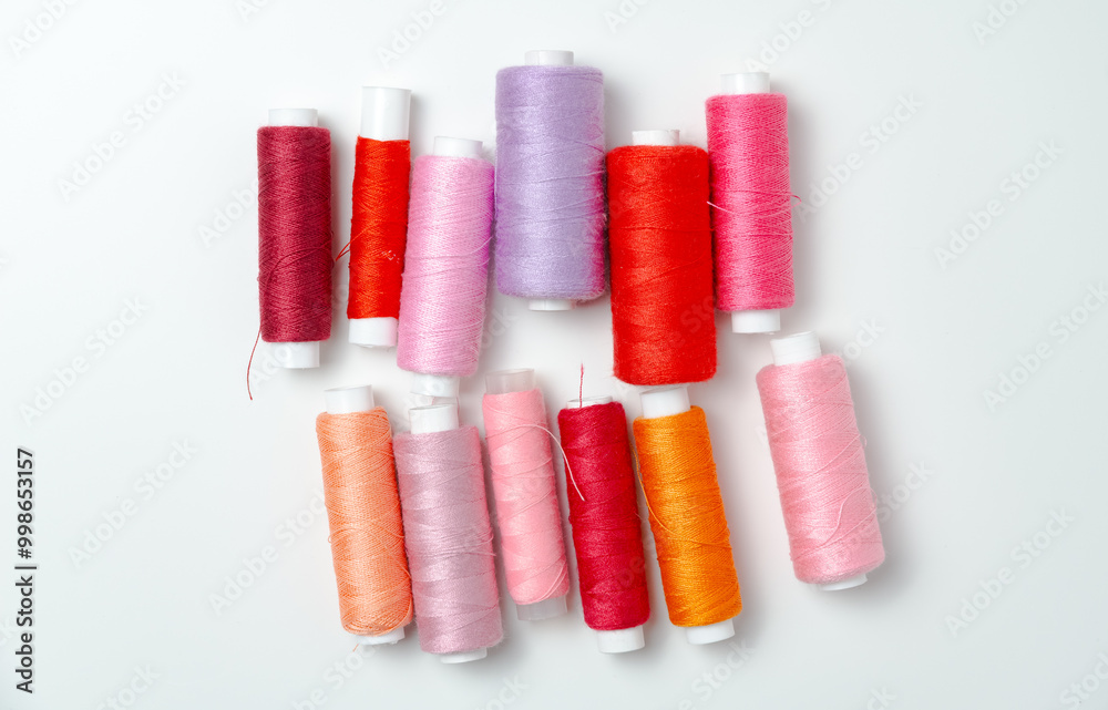 Pink and red thread spools on white background. Pink and red thread spools on white background.