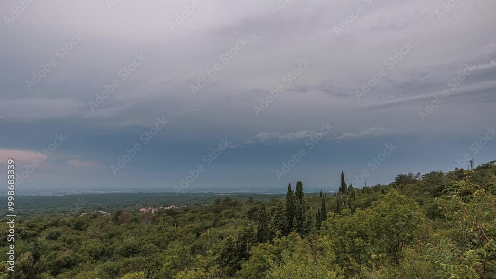 lungo timelapse video, con vista panoramica su parte del vasto territorio tra pianura e collina nel nord est Italia, di sera, in estate, con cielo nuvoloso e scuro, all'arrivo di un temporale