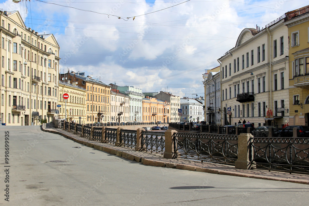 Obraz premium A picturesque street view along an embankment with historic buildings in a European city. The calm atmosphere and traditional architecture create a serene urban landscape.