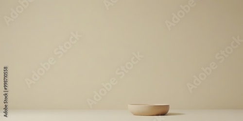 A simple beige bowl sits on a light-colored surface, casting a subtle shadow on the floor.