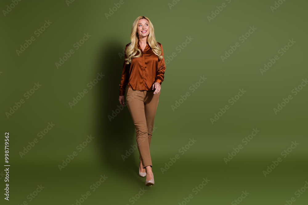 Full length photo of charming lovely nice woman wear silky trendy clothes look empty space isolated on khaki color background Full length photo of charming lovely nice woman wear silky trendy clothes look empty space isolated on khaki color background
