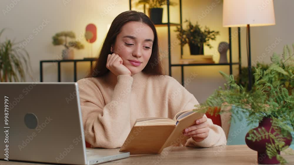 Caucasian young woman reading interesting book, turning pages smiling enjoying literature, taking a rest sits at table desk. Portrait of peaceful cheerful girl relaxing at home apartment living room Caucasian young woman reading interesting book, turning pages smiling enjoying literature, taking a rest sits at table desk. Portrait of peaceful cheerful girl relaxing at home apartment living room