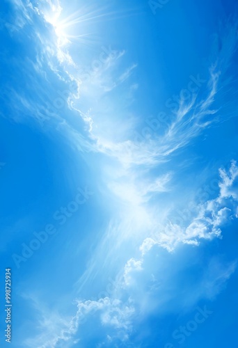 A serene blue sky with fluffy white clouds, where the sun's rays are shining through the top left corner, creating a beautiful and peaceful atmosphere photo