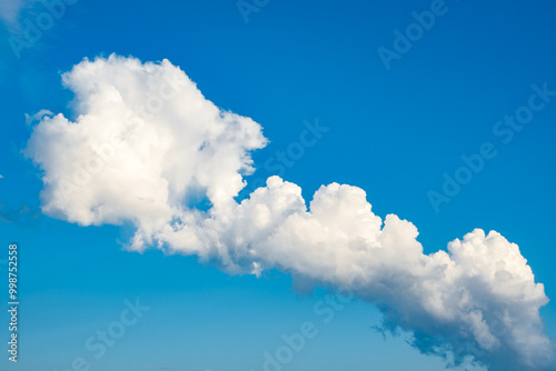 white cumulus clouds of bizarre shape in blue sky