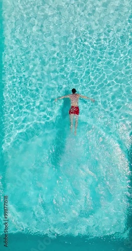 Aerial view as a man dives into the pool and swims. Slow motion