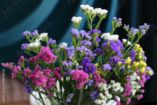 Bouquet of multicolored flowers in a vase (Limonium sinuatum, Statice sinuata) on a green background photo