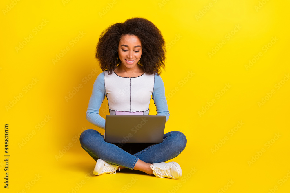 Full length photo of lovely young lady sit floor netbook dressed stylish blue garment isolated on yellow color background Full length photo of lovely young lady sit floor netbook dressed stylish blue garment isolated on yellow color background