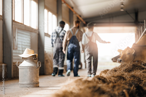 Owner farmer and happy team farm workers at cowhed. Portrait of group smiling young people standing in livestock barn
