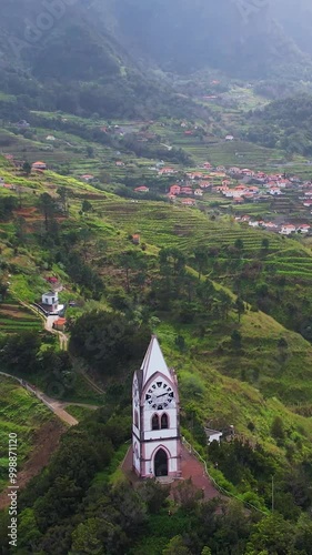 Historic clock tower Capelinha de Nossa Senhora de Fatima surrounded by lush green terraced landscape and blue ocean Madeira island Portugal photo