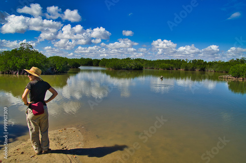 Middle aged woman looking out over a bay, bordered by mangrove forest. Cape Keraudren Coastal Reserve, a remote area in the Pilbara between Port Hedland and Broome in Western Australia.
