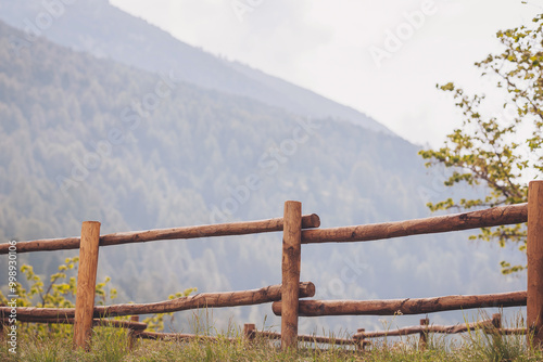 Wooden palisade on the mountain ridge. Close-up shot of old log fence. Brown wooden fence. Woooden walkway and Mountain with sky  photo