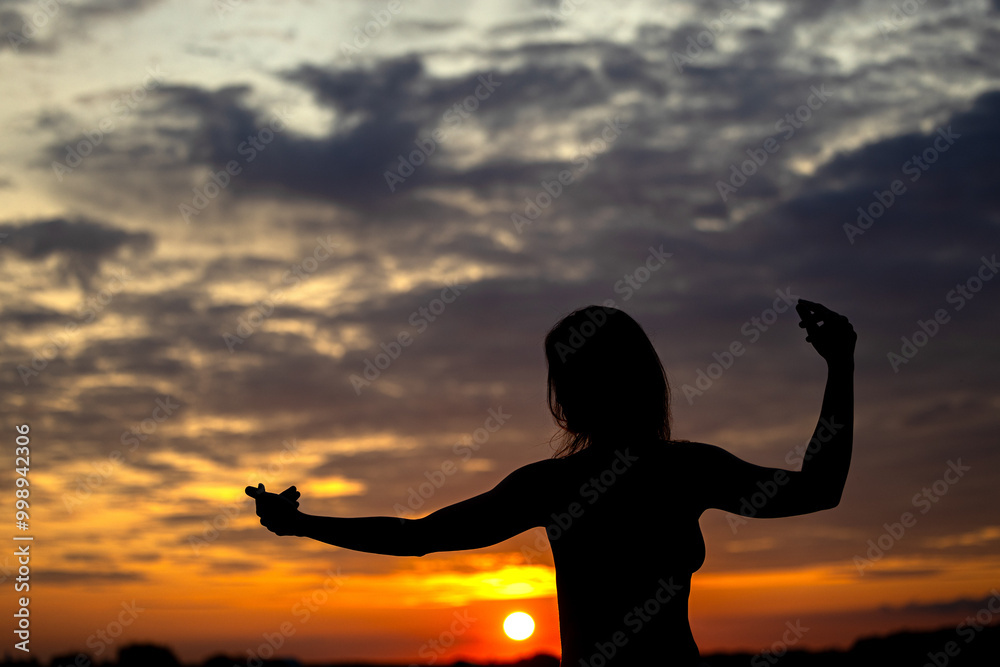 Fototapeta premium A woman's silhouette against the evening sky, with a stunning autumn-colored sky
