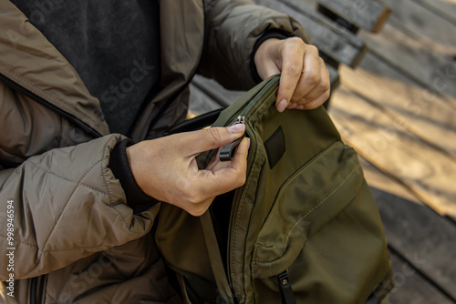 Woman opens or closes a backpack. Natural