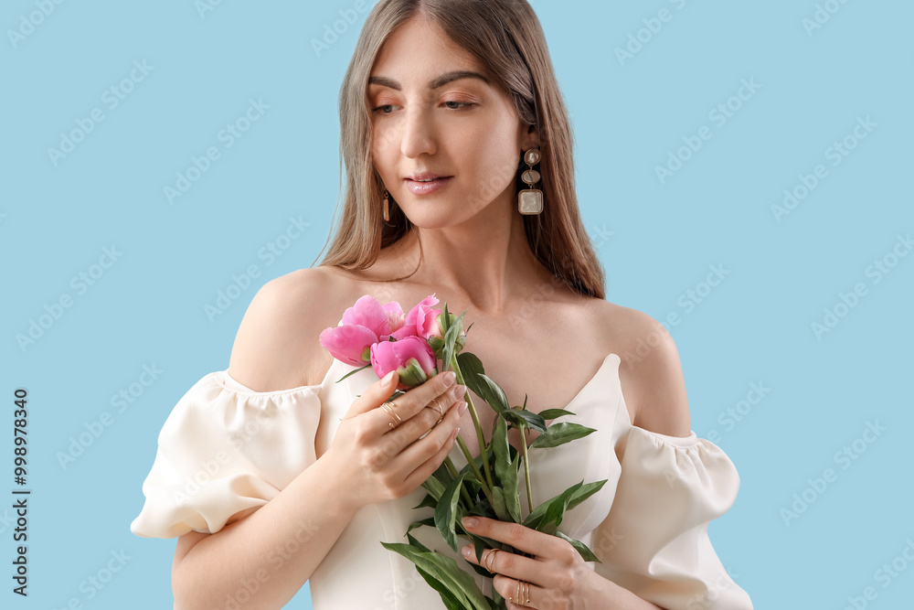 Beautiful young woman with peony flowers on blue background Beautiful young woman with peony flowers on blue background