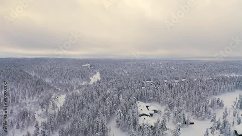 A breathtaking view of a snowy landscape in Lapland, showcasing dense forests blanketed in white under a gray sky. The untouched beauty invites winter adventure.	
