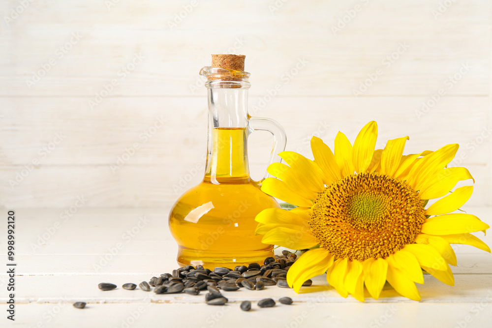 Decanter of sunflower oil and seeds on white wooden background Decanter of sunflower oil and seeds on white wooden background